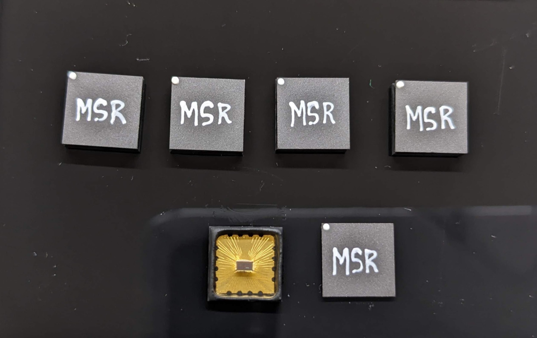Multiple packaged MRAM IMC test chips, including open-lid packages showing the bonded die